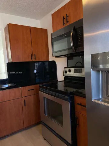 a kitchen with stainless steel appliances granite countertop a stove microwave and sink