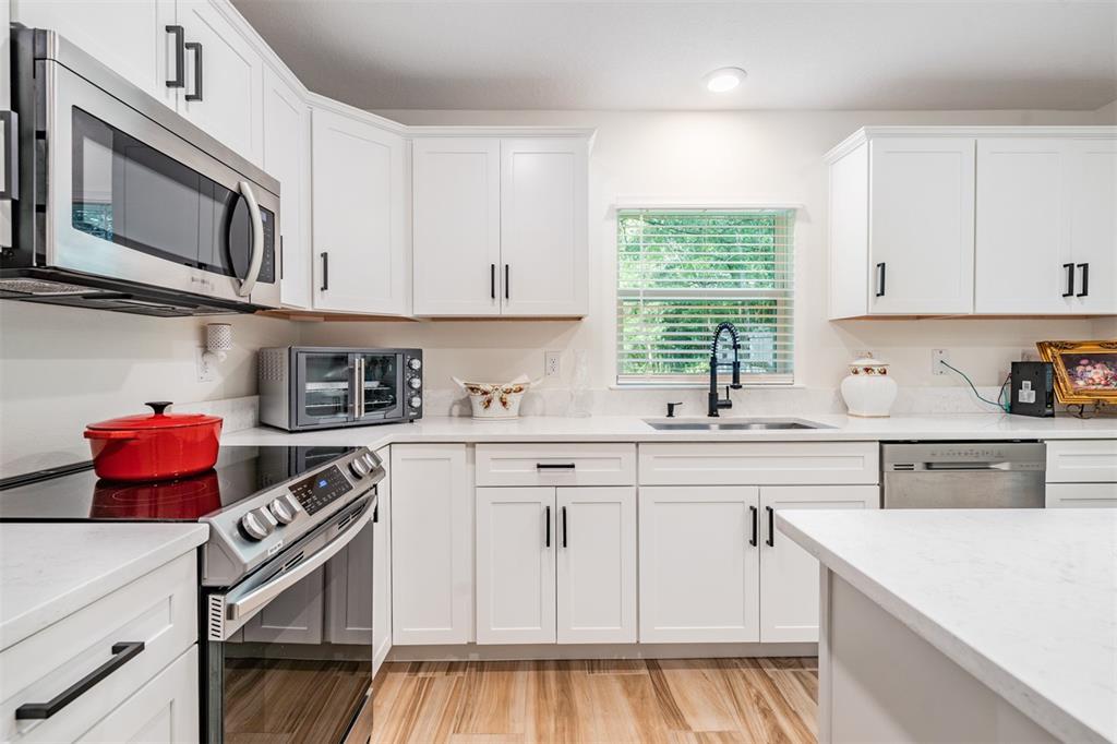 17415 Sweetwater Road Dade City, FL 33523 - Photo 36 of 72 a kitchen with stainless steel appliances white cabinets and a window
