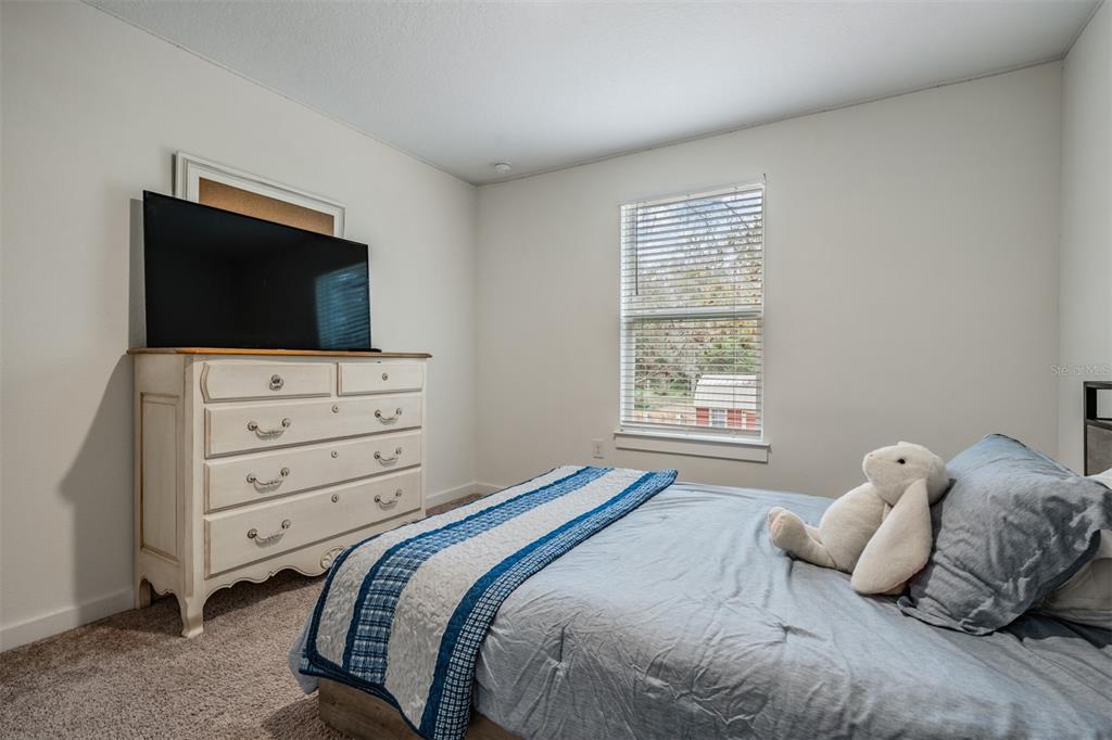 17415 Sweetwater Road Dade City, FL 33523 - Photo 62 of 72 a bedroom with a bed and flat screen tv