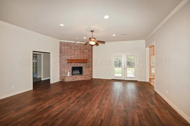 a view of an empty room with wooden floor fireplace and a window