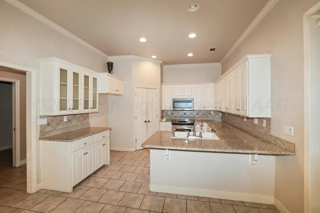 a kitchen with granite countertop a sink a stove and cabinets