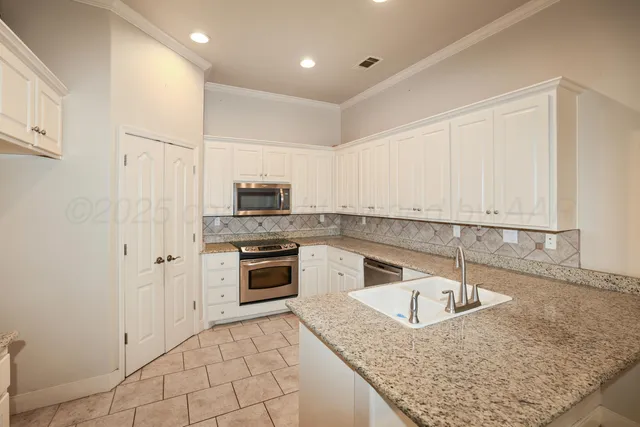 a kitchen with granite countertop a sink a stove and a refrigerator