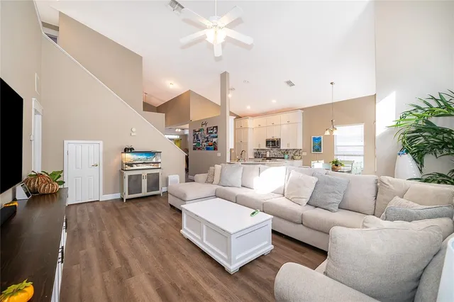 a living room with furniture kitchen view and a wooden floor