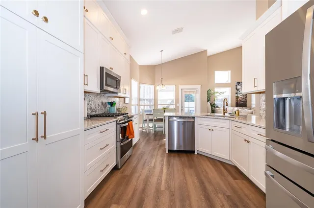 a kitchen with granite countertop a refrigerator stove top oven and sink
