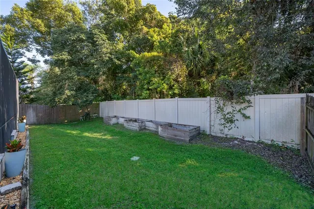 a backyard of a house with lawn chairs plants and tree