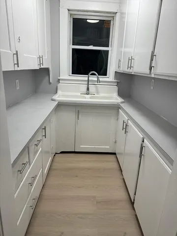 a kitchen with granite countertop white cabinets and a sink