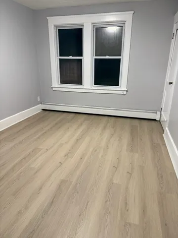 a view of an empty room with wooden floor and window