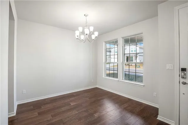 a view of an empty room with wooden floor and windows