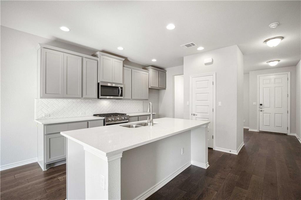 1616 Turtle Bay Loop Leander, TX 78641 - Photo 5 of 33 a kitchen with a sink a stove a refrigerator a center island and a window