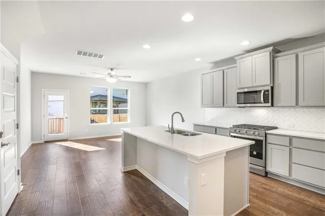a kitchen with stainless steel appliances granite countertop a sink stove and microwave