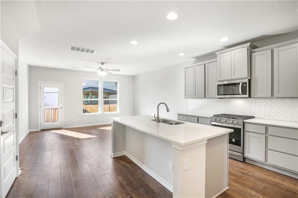 1616 Turtle Bay Loop Leander, TX 78641 - Photo 6 of 33 a kitchen with stainless steel appliances granite countertop a sink stove and microwave