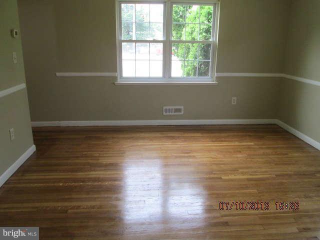 601 Crosby Road Baltimore, MD 21228 - Photo 8 of 16 a view of empty room with wooden floor and fan