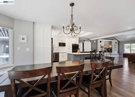 a kitchen with a stove a refrigerator and a dining table with wooden floor
