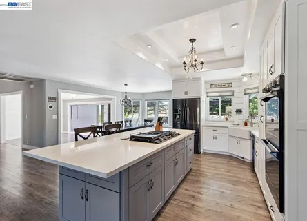 a kitchen with a stove a sink dishwasher a refrigerator with white cabinets and wooden floor