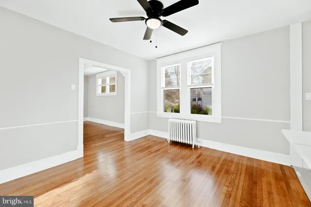 a view of an empty room with window and wooden floor