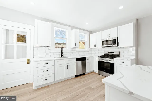 a kitchen with granite countertop white cabinets and stainless steel appliances