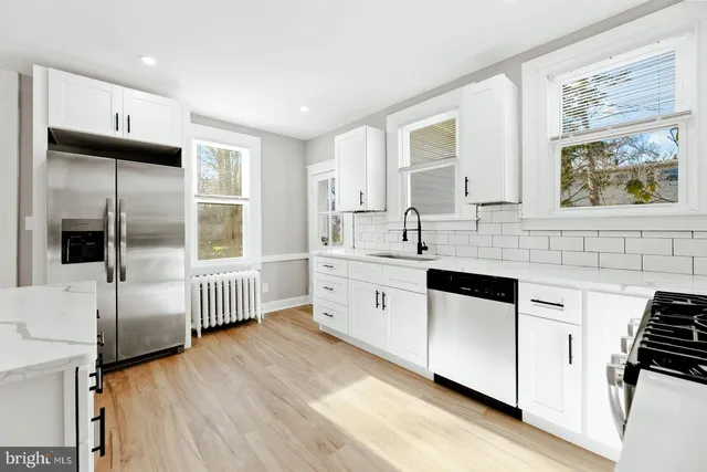 a kitchen with stainless steel appliances white cabinets and wooden floors