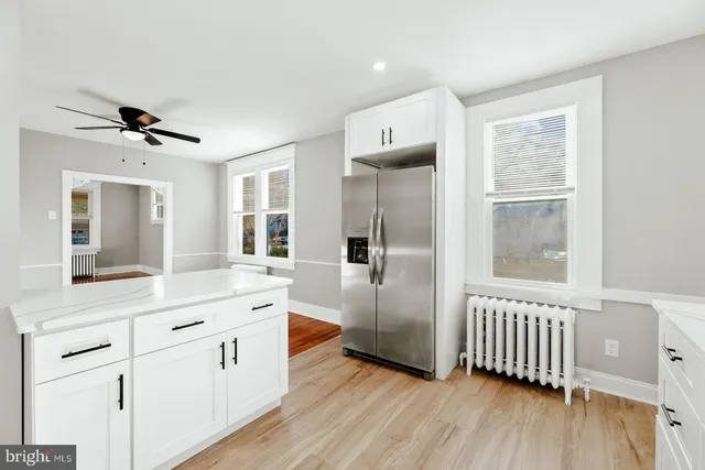 a view of a hallway with wooden floor and a bathroom