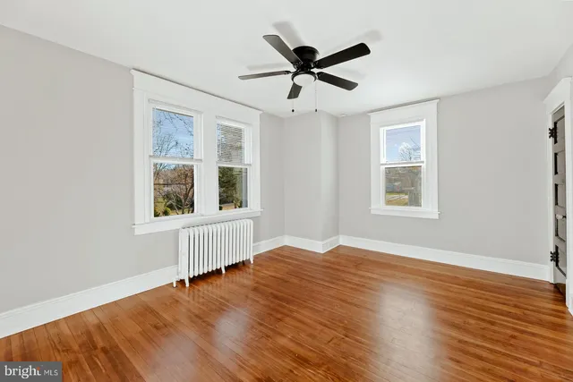 a view of empty room with wooden floor and fan