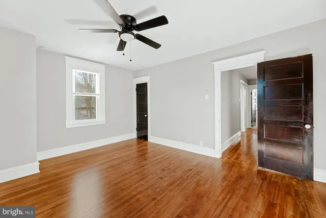 a view of an empty room with a window and wooden floor