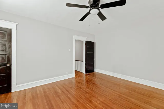 an empty room with wooden floor ceiling fan and windows