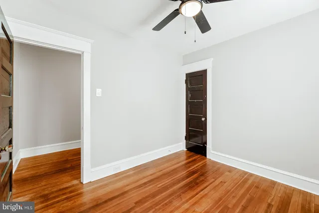 an empty room with wooden floor closet and windows