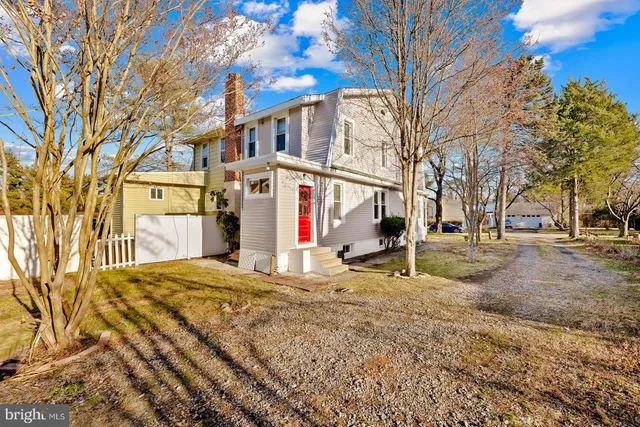 a view of a white house with a large tree