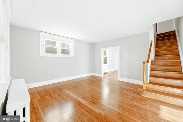 a view of an empty room with wooden floor and stairs