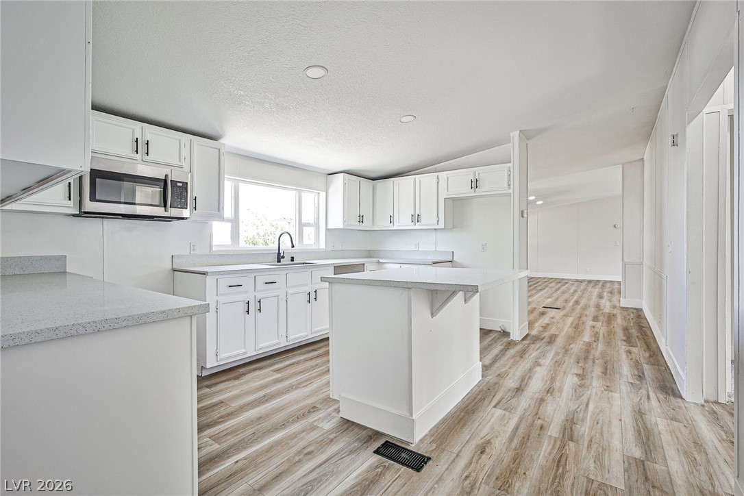 273 Aztec Lane Henderson, NV 89015 - Photo 4 of 28 A well-appointed kitchen boasts sleek countertops, white cabinetry, and durable wood-look flooring.