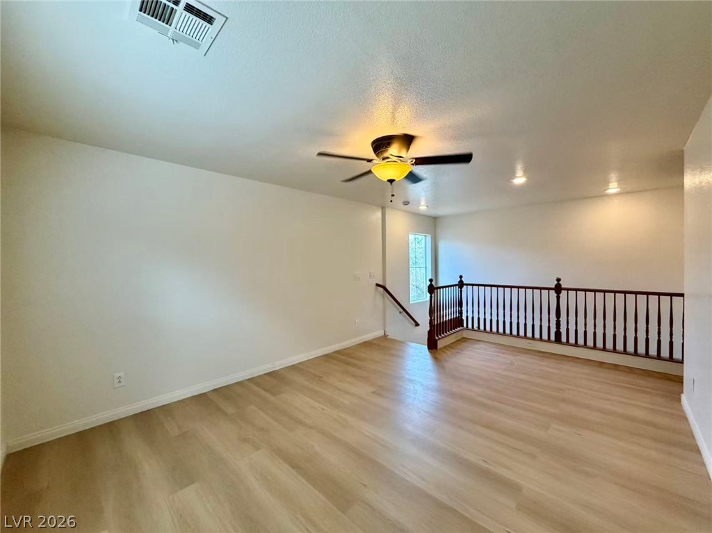 11183 Ranch Valley Street Las Vegas, NV 89179 - Photo 5 of 19 A versatile open-concept living space features light wood flooring, a ceiling fan, and staircase with wooden railing.