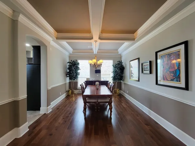 a dining room with wooden floor a chandelier a glass table and chairs
