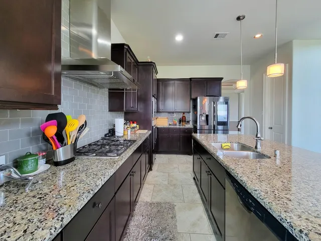 a kitchen with stainless steel appliances granite countertop a sink stove and cabinets