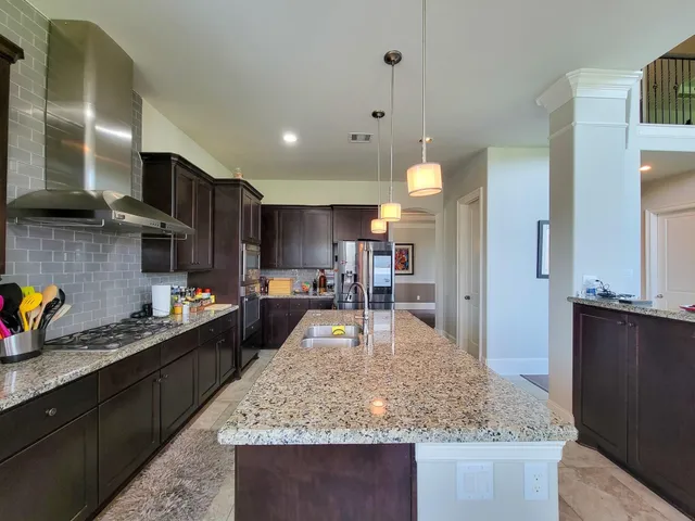 a kitchen with stainless steel appliances granite countertop sink stove top oven and cabinets