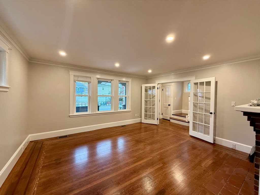 224 Faneuil Street, Unit 1 Boston, MA 02135 - Photo 2 of 19 a view of an empty room with a window and wooden floor