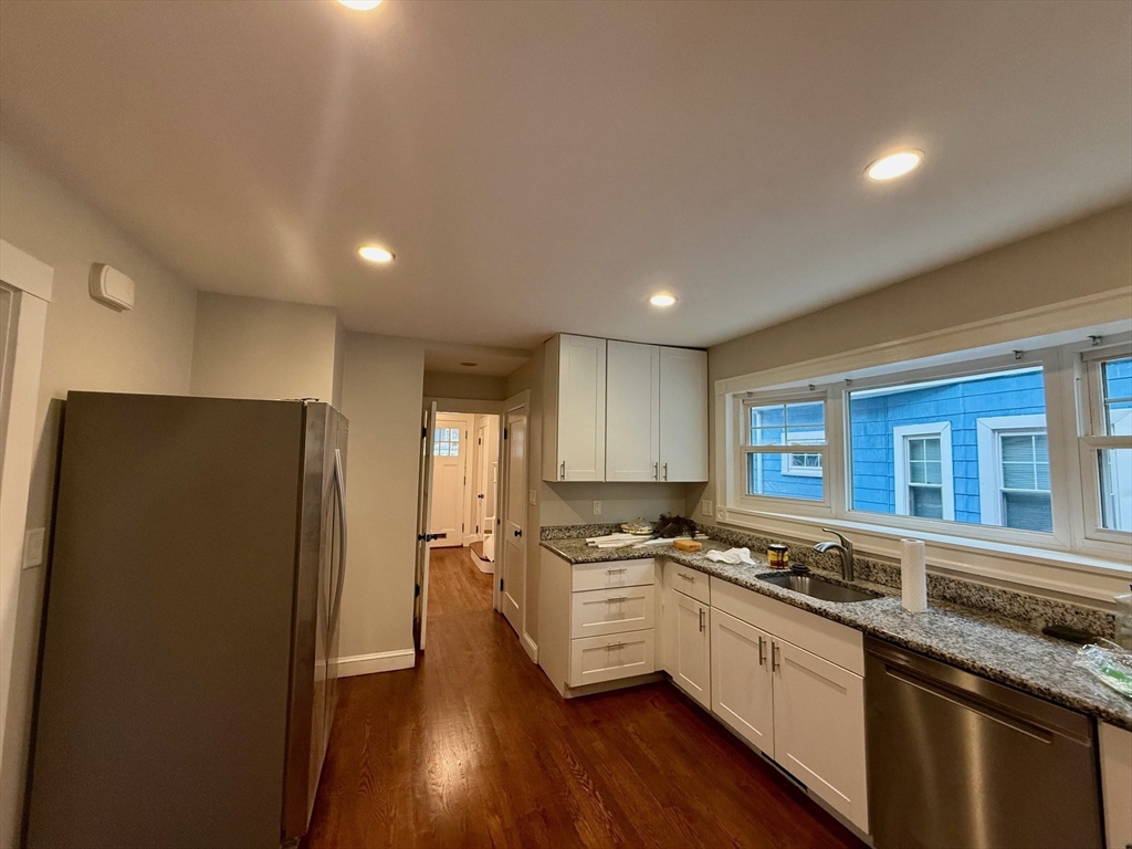 224 Faneuil Street, Unit 1 Boston, MA 02135 - Photo 8 of 19 a kitchen with stainless steel appliances granite countertop a refrigerator a sink dishwasher a stove and white countertops with wooden floor