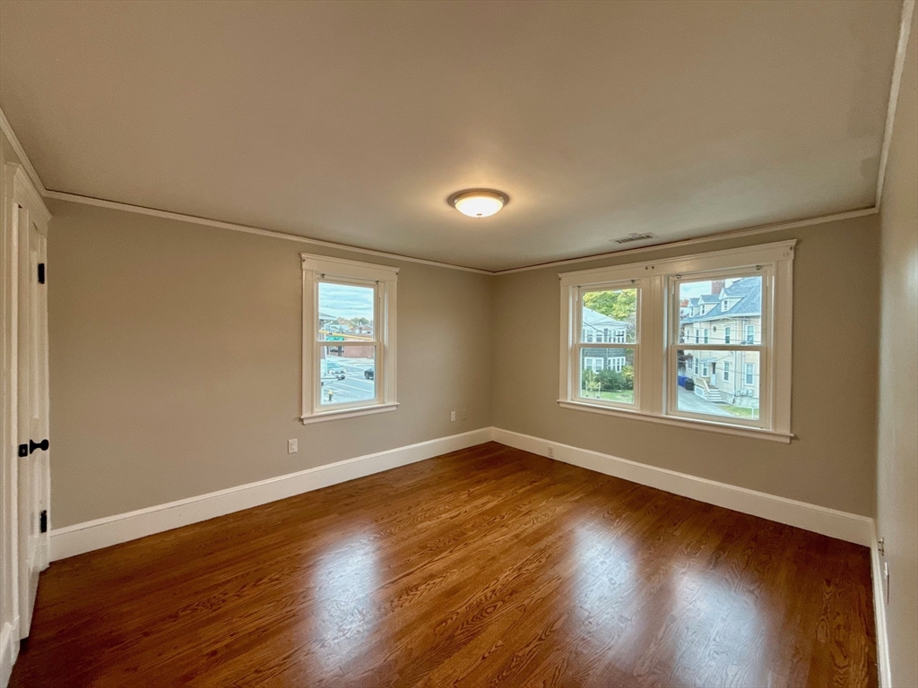 224 Faneuil Street, Unit 1 Boston, MA 02135 - Photo 10 of 19 a view of an empty room with wooden floor and a window