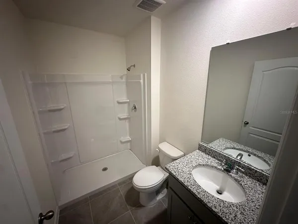 a bathroom with a granite countertop sink toilet and shower