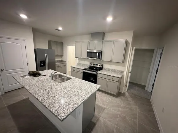 a kitchen with kitchen island granite countertop a sink stove and refrigerator