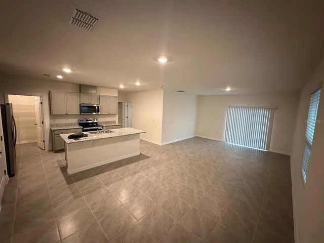 a large white kitchen with kitchen island a sink stainless steel appliances and a counter top
