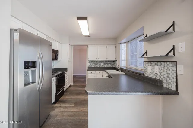 a kitchen with stainless steel appliances granite countertop a sink a stove and a refrigerator