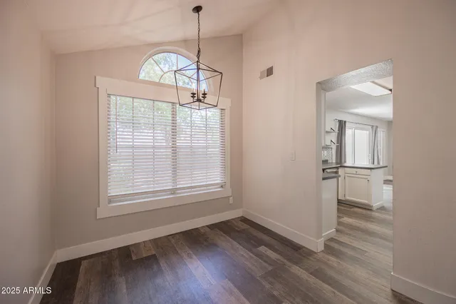 a view of empty room with wooden floor and window