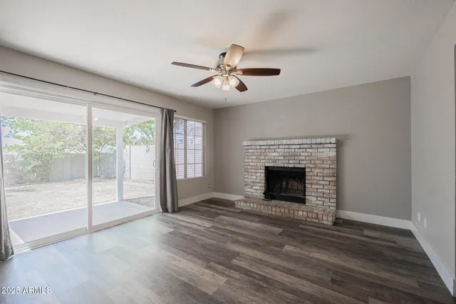 a view of a livingroom with a fireplace a ceiling fan and window