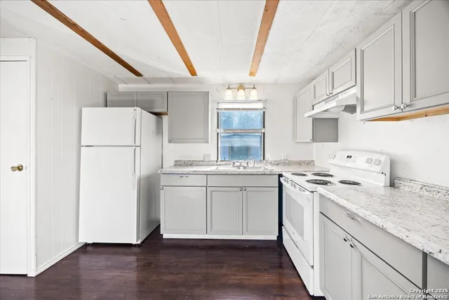 a kitchen with a sink a white refrigerator a stove and a wooden floors
