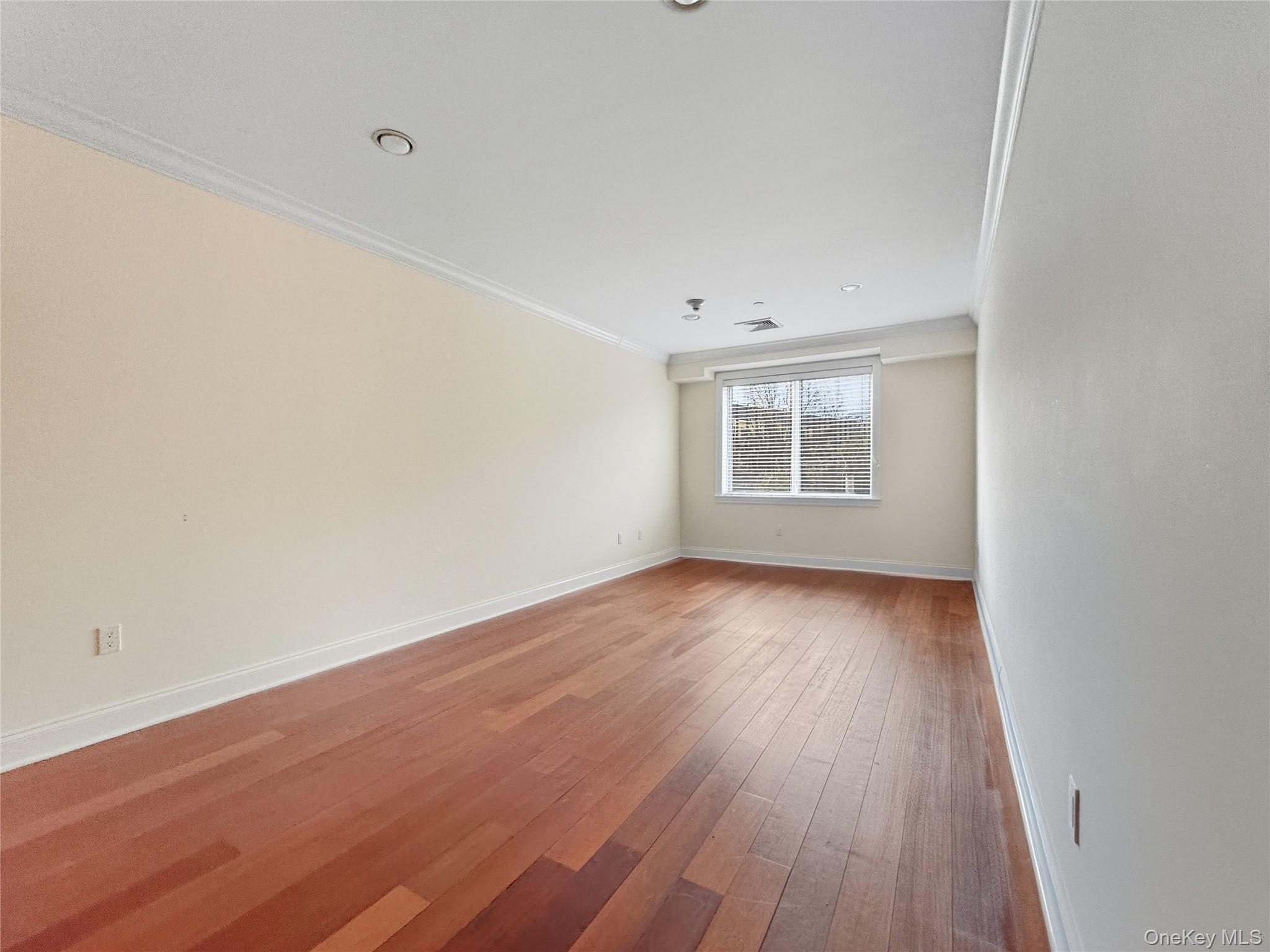 171 Great Neck Road, Unit 1C Great Neck, NY 11021 - Photo 5 of 17 an empty room with wooden floor and windows