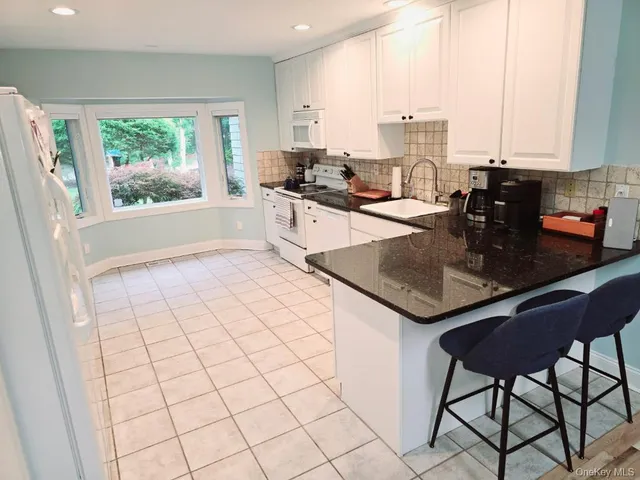 a kitchen with stainless steel appliances a refrigerator a sink a stove a window and white cabinets