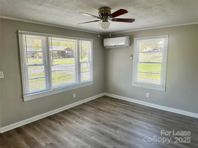 a view of an empty room with a window and wooden floor