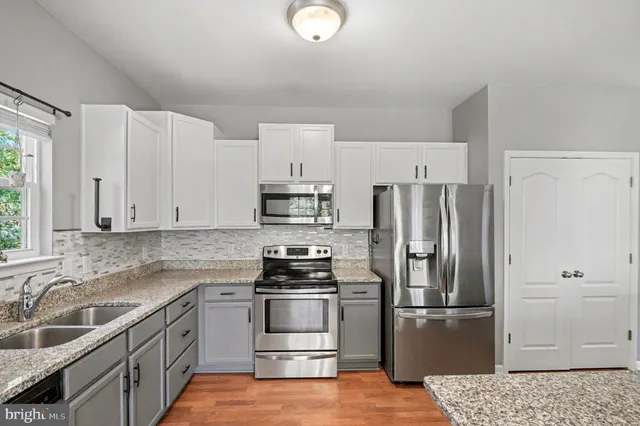 a kitchen with granite countertop a refrigerator stove and sink