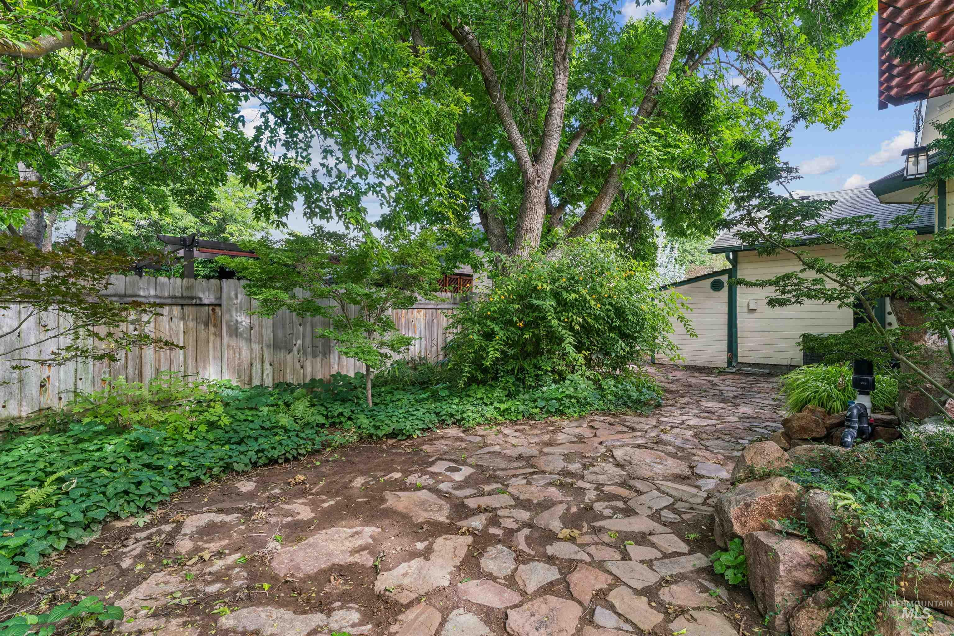 9831 West Ripley Street Boise, ID 83704 - Photo 40 of 47 Exterior patio with a wood pergola, stone-edged paver pathway, and mature landscaping