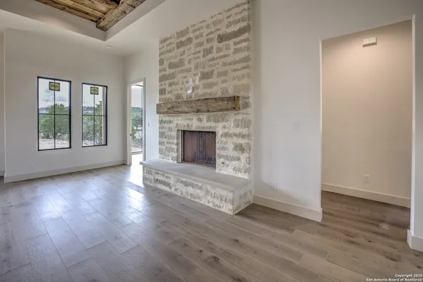 an empty room with wooden floor fireplace and windows