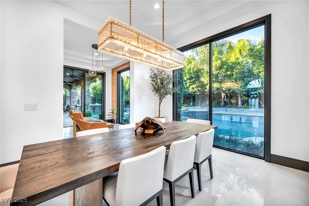 8032 Spring Buck Court Las Vegas, NV 89129 - Photo 12 of 41 Dining area with crown molding, light marble finish floors, a ceiling fan, and a chandelier